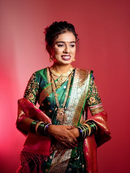 A studio shot of the bride in a green and red Nauvari saree, with dramatic lighting to highlight her features.