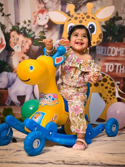 Our Jungle Safari theme includes fun props for kids to play with, like this giraffe rocker. The backdrop features friendly cartoon animals, creating a playful atmosphere for a pre-birthday photoshoot.