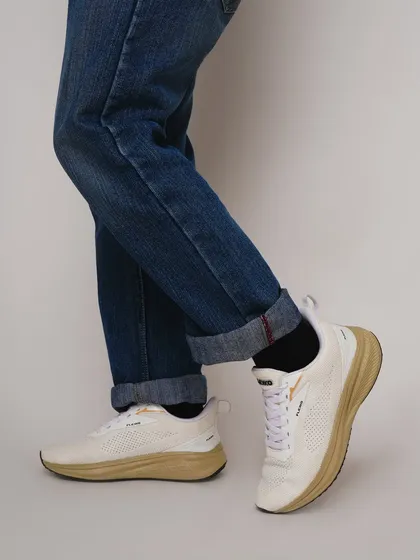 An on-foot shot of white sneakers paired with classic blue jeans. This is a timeless lifestyle look that helps customers visualize how they can style the shoes in their own wardrobe.