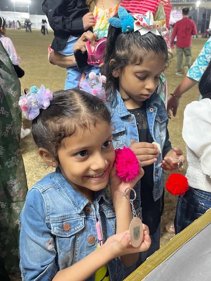 Young children excited about their handmade keychains at a school carnival booth. I offer various DIY activities like this to keep kids engaged and creative.