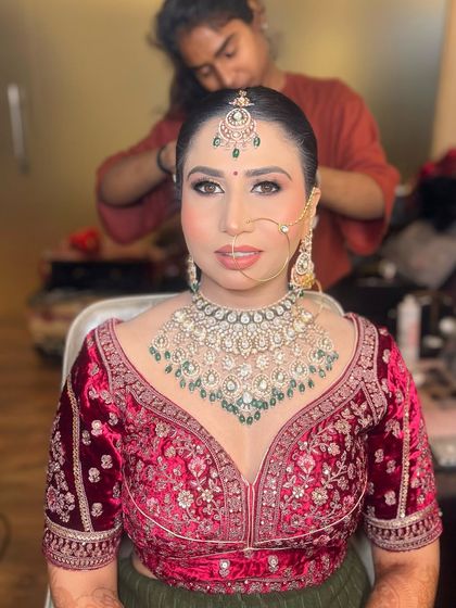 Another shot of the same bride, capturing a candid moment as her hair is being styled. Her makeup is complete and looks flawless.