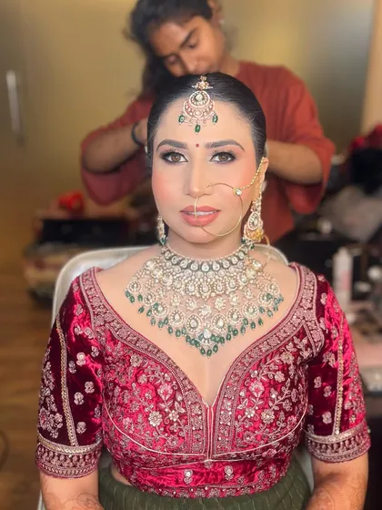Another shot of the same bride, capturing a candid moment as her hair is being styled. Her makeup is complete and looks flawless.