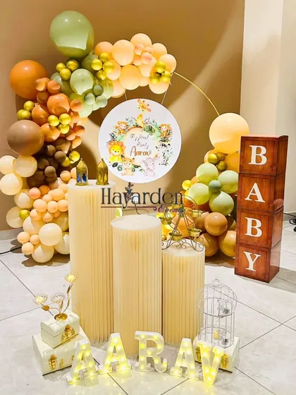 An elegant take on the jungle theme, using a half-ring balloon garland in muted earth tones. The setup includes 'BABY' blocks and light-up letters.