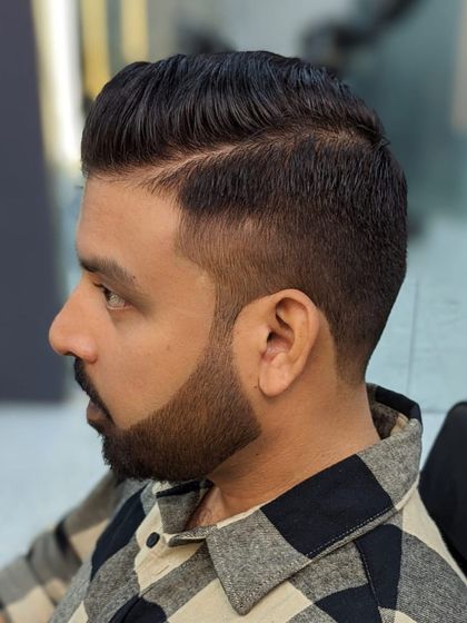 A sharp, professional look featuring a classic side part with a skin fade. The beard is meticulously shaped to complement the haircut, resulting in a clean and timeless style.