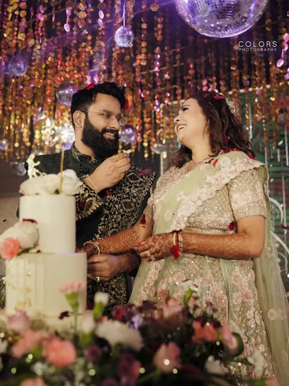 A sweet moment during the cake-cutting ceremony at the reception. The disco balls and glittering backdrop add to the celebratory feel.