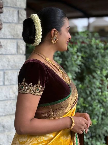 A client showcasing the rich texture of a puff-sleeved velvet blouse. The intricate gold embroidery on the sleeve cuff adds a touch of luxury, making it ideal for a reception or grand event.