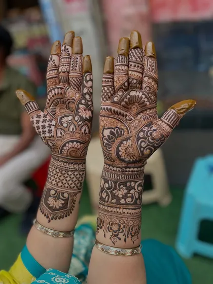 A classic bridal design with a mix of floral, paisley, and geometric patterns. The henna paste is still on, showing the artwork in its fresh form.