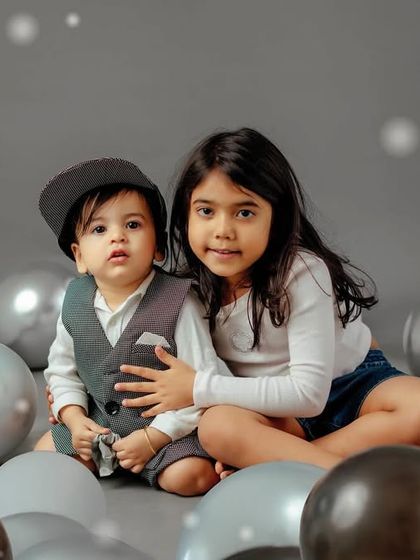 A sweet portrait of a sister and her baby brother surrounded by balloons. Sibling photoshoots are a wonderful way to celebrate their growing bond.