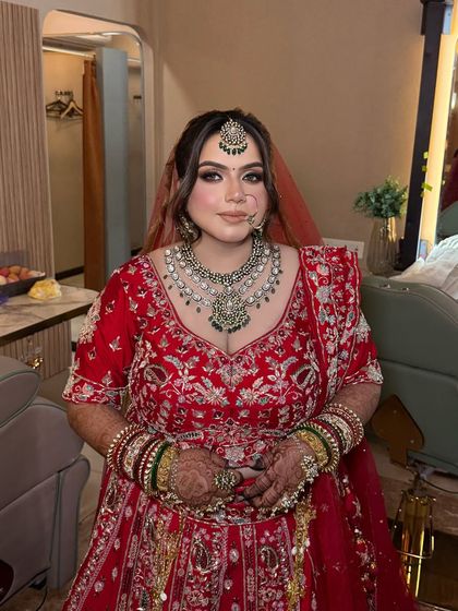 My radiant bride looking absolutely stunning. Her makeup features bold, smoky eyes and a contoured base, perfectly matching the grandeur of her red and silver embroidered lehenga.
