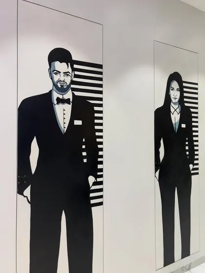 The pair of washroom murals seen together, creating a cohesive and clever design element within the office corridor.