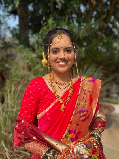 A beautiful bride in a traditional red Paithani saree. The makeup is classic and elegant, with a focus on her radiant smile.