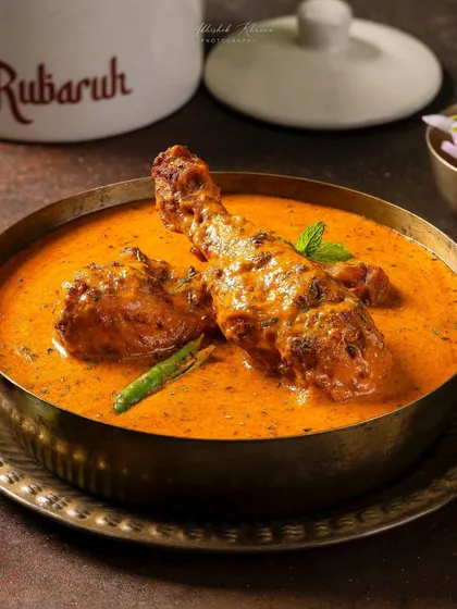 A close-up of Chicken-e-Rubaruh, a signature creamy chicken curry. This shot for Rubaruh highlights the rich gravy and tender chicken, styled in traditional brassware to reflect the brand's identity.