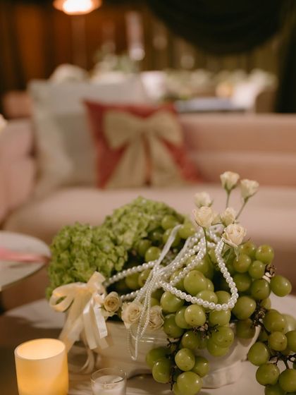A centerpiece detail combining green grapes, pearls, and white flowers, reflecting the "pearl and velvet" elegance of the night.