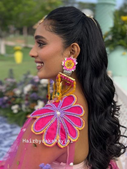 A fun and flirty high ponytail with soft waves, perfect for a colorful mehendi or haldi event.