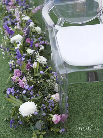 The aisle for the rooftop wedding was lined with a beautiful ground arrangement of purple, pink, and white flowers, adding color and life to the seating area.