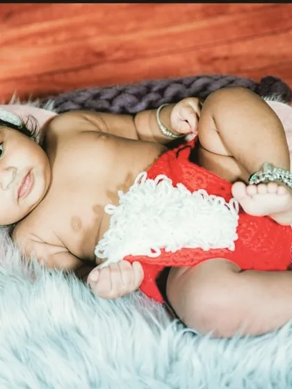 A festive baby portrait with the little one dressed in a cute Santa-themed outfit, perfect for a holiday-themed photoshoot.
