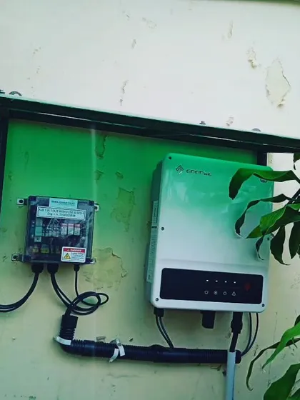 A completed inverter and net meter setup, protected by a green metal shield. We ensure all electrical components are securely mounted and shielded from the elements for reliable, long term operation.