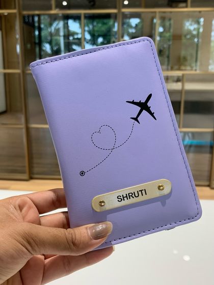 A personalized lavender passport cover with the name 'Shruti' and a cute airplane charm. A perfect Rakhi gift for a sister who loves to travel.