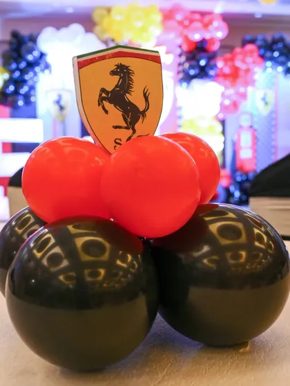 A close-up of a table centerpiece from the Ferrari party, featuring red and black balloons topped with the iconic Ferrari shield.