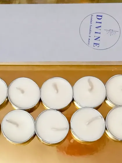 A pack of ten peach soy wax tealights, neatly arranged in front of their box. The silver aluminum containers are reflected on the gold surface below.