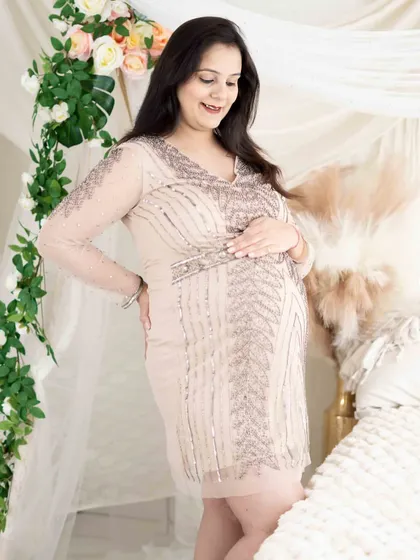 A soft and gentle lifestyle portrait. The mom-to-be, in a beautiful sequined dress, relaxes in our cozy bed setup, creating a dreamy and comfortable atmosphere.