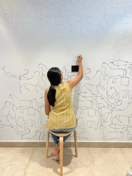 The beginning stages of the nursery doodle wall. This shot shows me meticulously hand-drawing the continuous line of animals, which will eventually cover the entire wall in a playful pattern.
