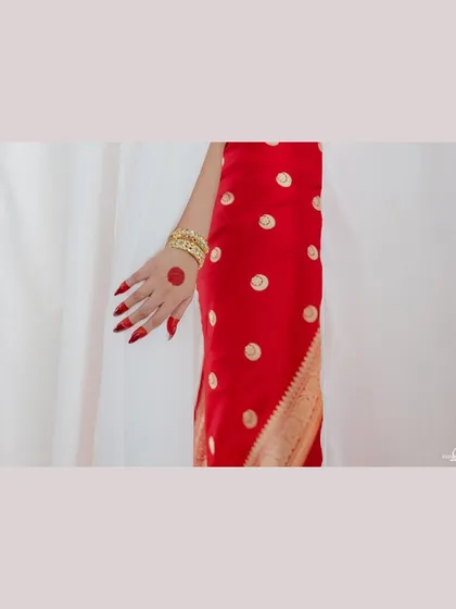 A detail shot of Sonakshi's hand, showing her alta and bangles against her red saree. These small details are an important part of the story of a bride's look.