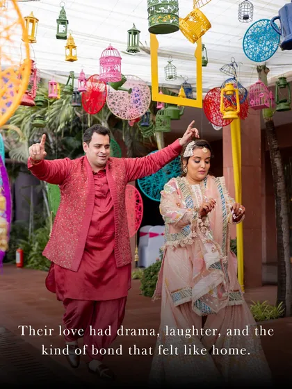 A fun, candid dance moment from a colorful Mehendi function, showcasing the couple's playful bond and the vibrant decor with hanging birdcages.