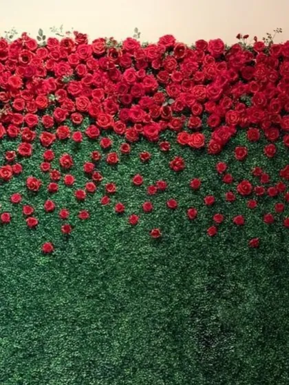 A unique and artistic floral wall design, this piece features red roses appearing to spill down over a lush green backdrop.