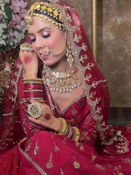 A full view of a bride in a red lehenga, adorned with a complete Rajasthani Kundan jewellery set. The look includes a choker, mathapatti, nath, and hathphool.
