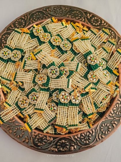 A tray of beautifully crafted brooches for the guests, combining pearls and green threadwork. These small, thoughtful details enhance the guest experience and tie into the overall wedding theme.