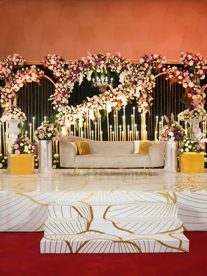 A truly grand reception stage, where arches of lush flowers are set against a backdrop of hundreds of glowing candles, creating an incredibly romantic and dramatic effect.