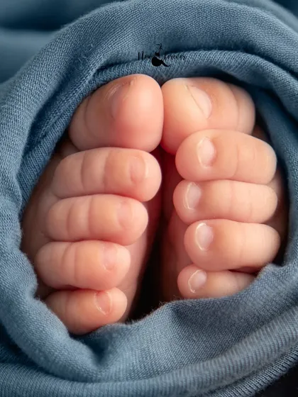 A macro shot of a newborn's tiny toes, perfectly curled and wrapped in a soft blue swaddle. These are the little details that tell the big story of their arrival.