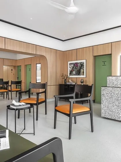 The reception and waiting area of Dr. Banerjee's Homeopathy Clinic. We used a minimalist approach with warm oak panels, a monolithic quartz desk, and clean lines to create a tranquil space that immediately puts patients at ease.