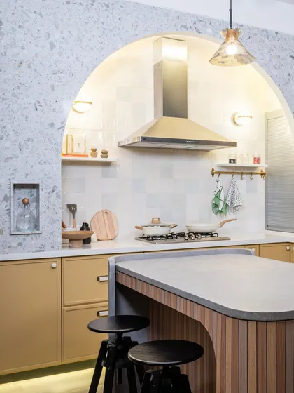 The arched cooking nook is the centerpiece of this kitchen. Lined with terrazzo, it creates a defined and elegant space for the hob and chimney, turning a functional area into a stunning focal point.