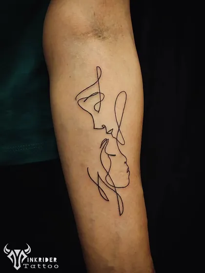 The beauty of minimalism is in its power to convey deep emotion with simple forms. This continuous single-line tattoo captures the intimacy of two faces, creating an abstract yet profoundly connected piece of art on the forearm.