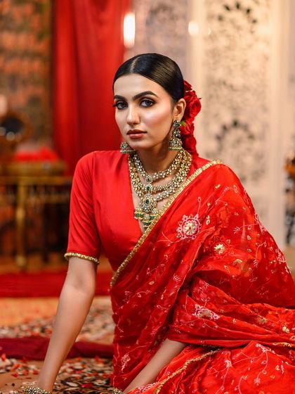 A full shot of a model in a vibrant red saree, a classic look I demonstrate for traditional events.