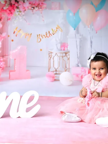 A perfect portrait from a first birthday shoot, capturing a beautiful smile from the birthday girl in her pink dress.