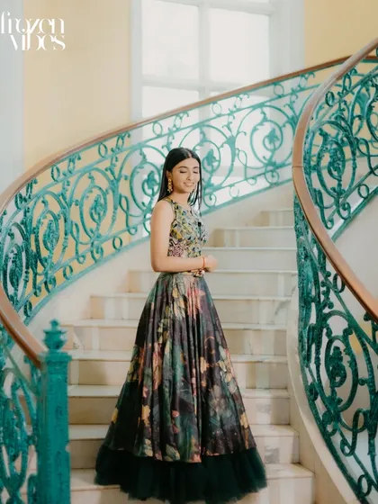 A beautiful solo portrait of the bride, Shikha, on a grand, winding staircase. The elegant setting complements her floral gown perfectly, creating a timeless and graceful image.