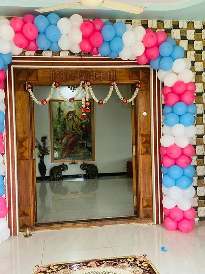 A welcoming entrance for a home baby shower, with a colorful balloon arch over the main door and a personalized sign.