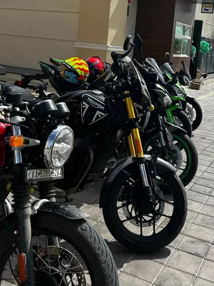 A row of touring and street motorcycles, including a Triumph, lined up and ready for the next leg of their journey after a refreshing break.