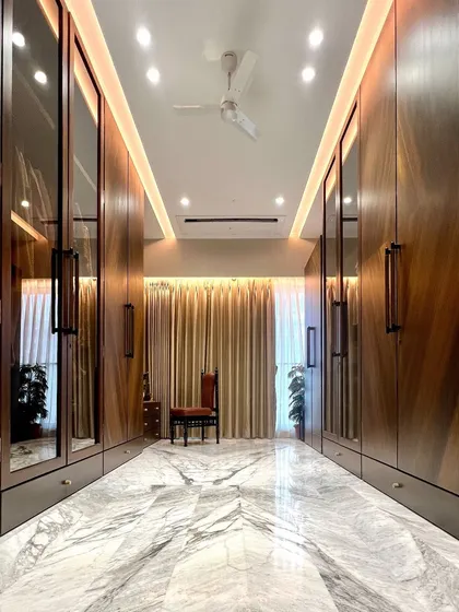 We believe a walk-in closet should feel like a private boutique. This expansive space features custom floor-to-ceiling walnut cabinetry with integrated mirrors, set against a book-matched marble floor, creating a perfect blend of functionality and opulence.