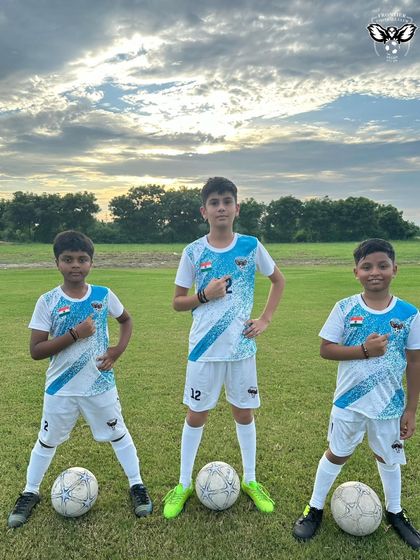 Three of our young players pointing to the club badge with pride. Join our academy to be part of this journey.