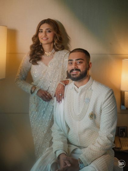 A sophisticated indoor portrait of a couple in elegant white outfits. The soft lighting and classic pose create a timeless and graceful image, perfect for capturing the dignity of a Nikaah ceremony.