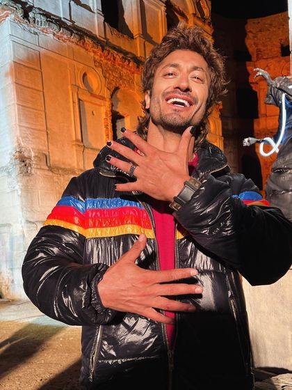 Vidyut Jammwal having a fun moment behind the scenes of "Crakk". This shot captures the great energy on set, even while he is in his character's costume, a retro-striped puffer jacket.