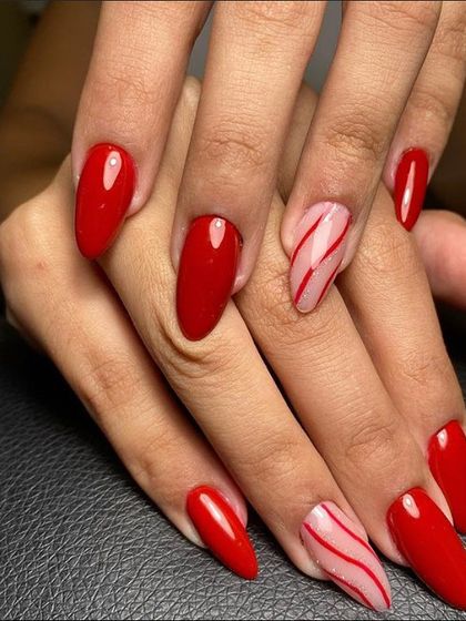 A classic red manicure with a twist. This set includes accent nails with candy cane-inspired red stripes on a sheer pink base.