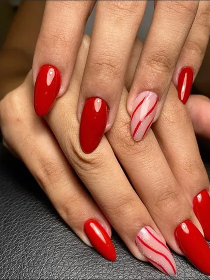 A bold red manicure with two accent nails featuring candy cane-like stripes for a festive touch.