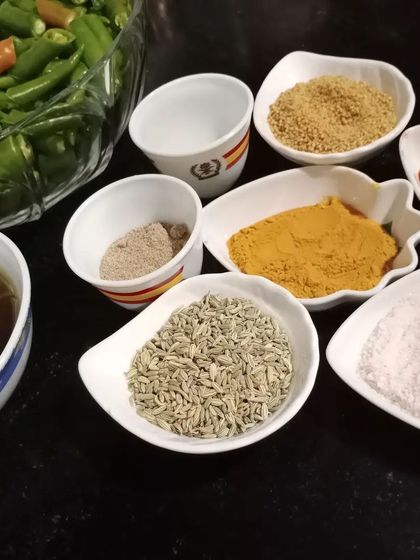 The spices for our green chilli pickle are laid out and ready to be mixed. We use fennel seeds, turmeric, salt, and other spices to create the perfect filling.