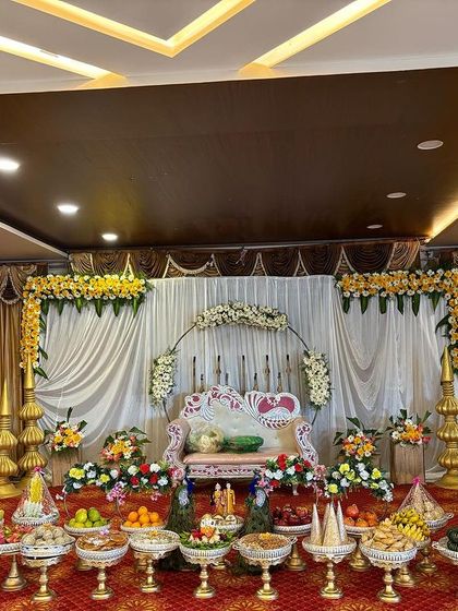 A simple stage with gold pillars and a white and gold curtain backdrop.