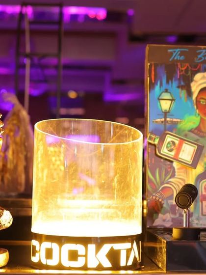 A close-up of the bar decor at a Diwali party. The small details, like this "Cocktail" sign and Buddha statue, add to the overall theme and ambiance.